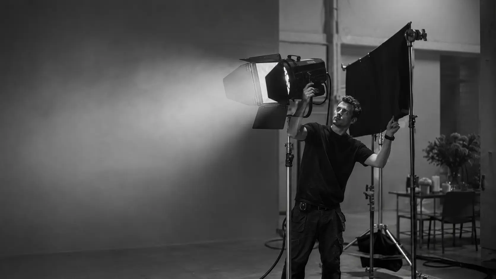 Oświetleniowiec regulujący lampę i flagę na planie filmowym